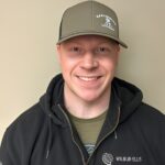 Smiling man wearing a cap and hoodie.